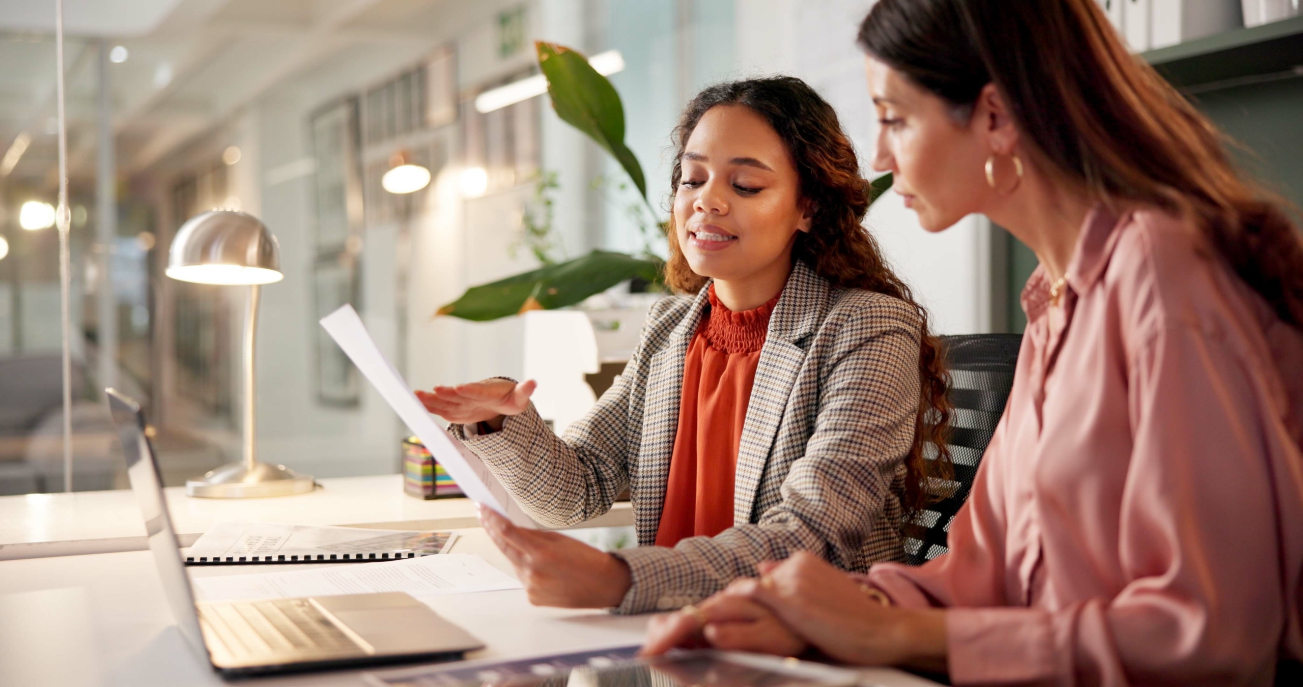 Two professionals collaborate in a modern office, reviewing documents together—illustrating how outsourced financial teams support strategic planning and HR functions.
