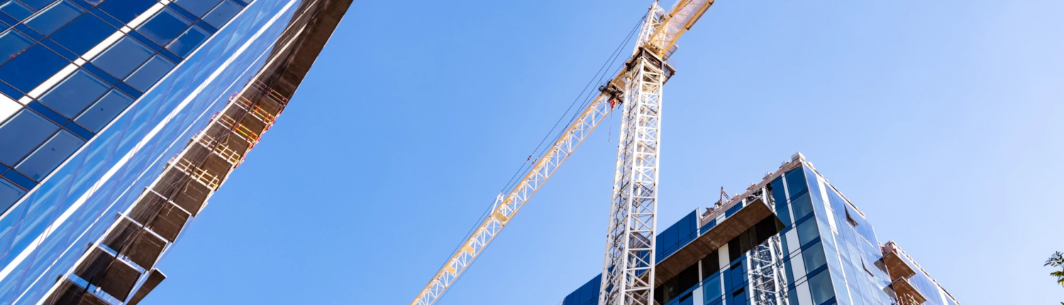 Tower crane between commercial buildings under construction.
