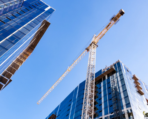 Tower crane between commercial buildings under construction.