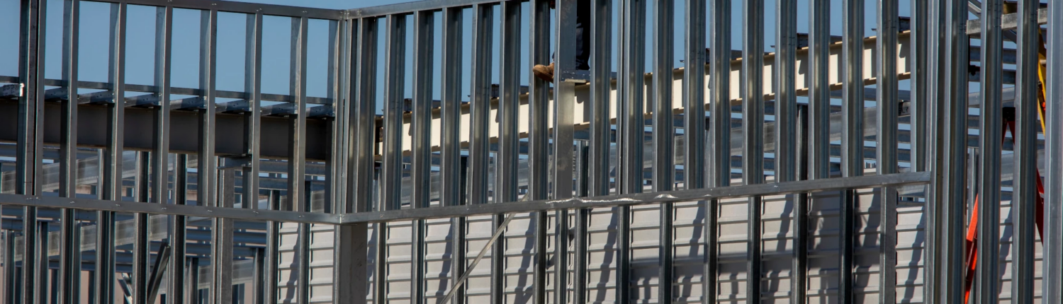 Construction worker installing metal framing on a building under construction.