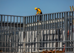 Construction worker installing metal framing on a building under construction.