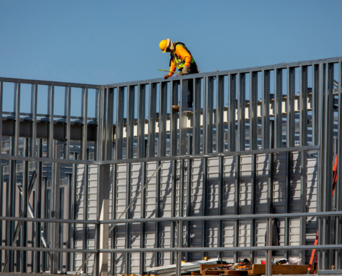 Construction worker installing metal framing on a building under construction.